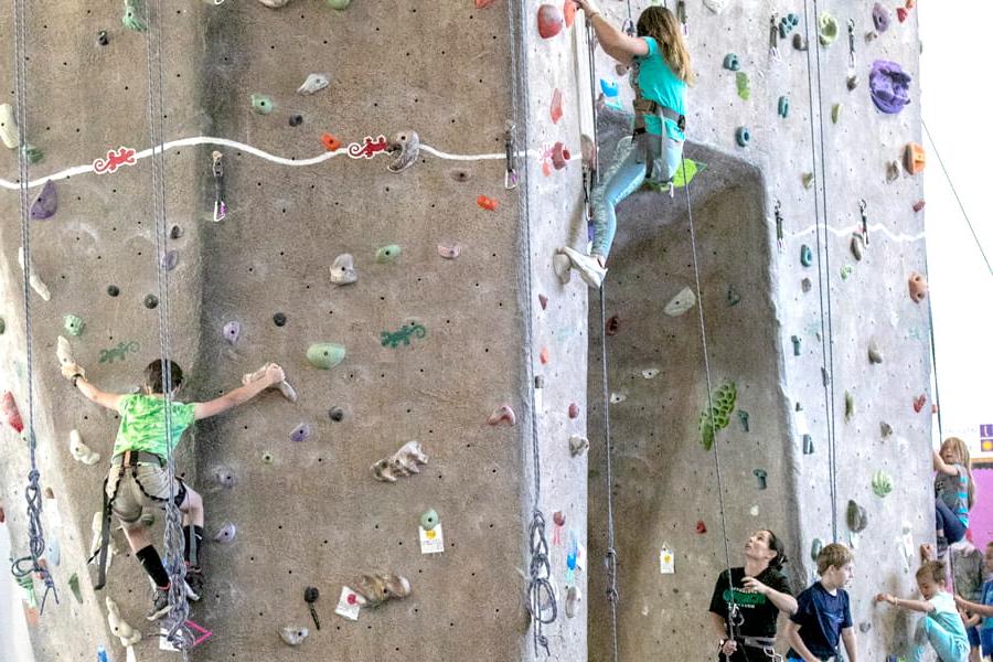 Two kids climbing the indoor rock wall at the Health and Human Performance Center