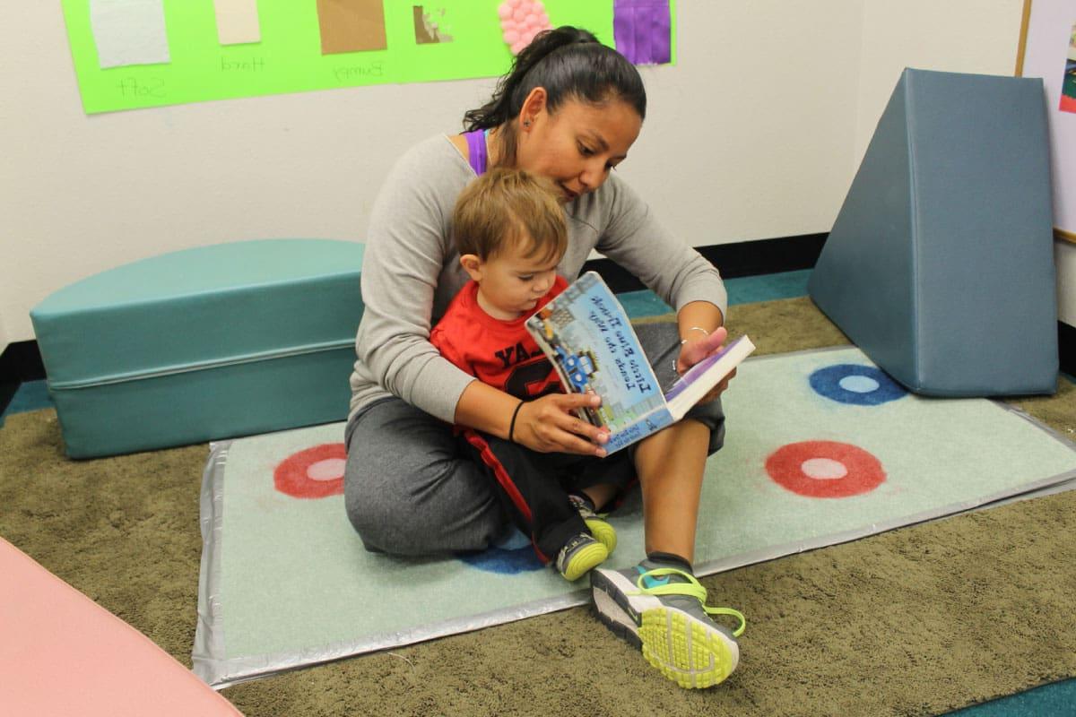 An SJC Child and Family Development Center Instructor reading to a toddler in the Toddler Classroom